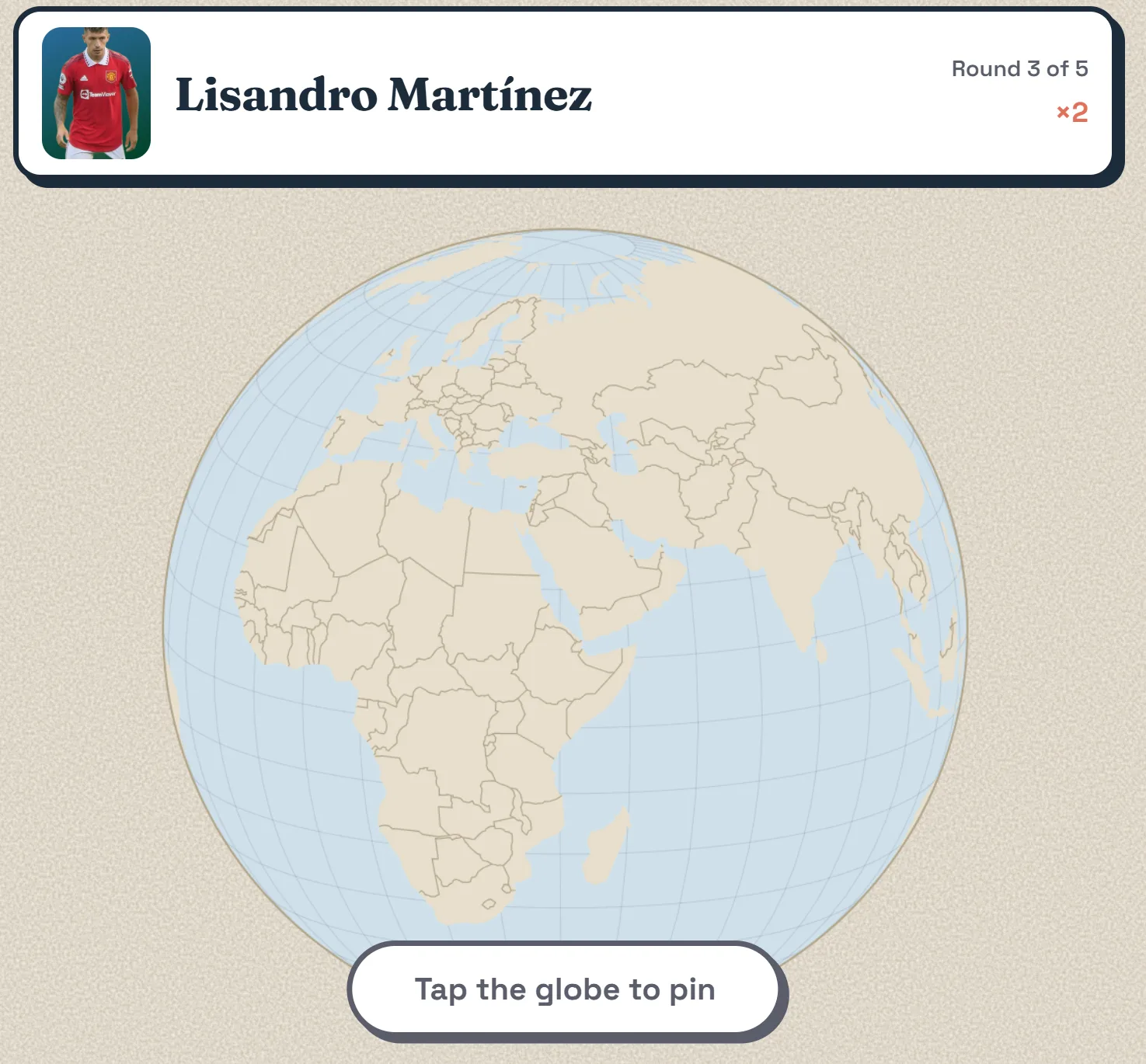 The Grassroots globe: an orthographic world map centred on Africa and Europe, with Lisandro Martínez's face and name above it and a 'Tap the globe to pin' prompt below